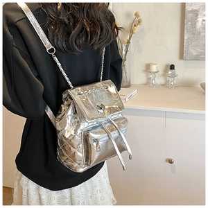 Detail of silver quilted backpack with heart-shaped lock and metal chain straps