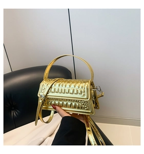 Close-up of metallic gold handbag with quilted texture and silver side hardware detail