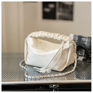 Détail de la poignée froncée et de l'imprimé floral sur le sac bandoulière beige