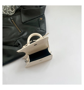 Detail view of cream mini bag showing silver magnetic closure and interior lining