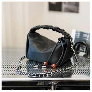 Détail d'un sac à main en cuir plissé noir avec cordon en perles d'ambre et chaîne argent