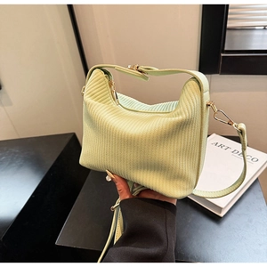 Détail du sac à main plissé vert clair montrant la texture tissée et la bandoulière amovible