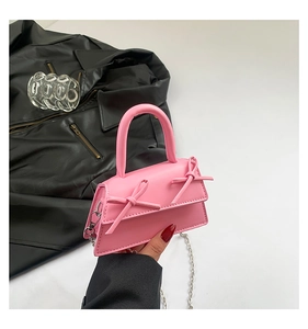 Detail of a pink mini crossbody bag featuring dual bows and a silver metal chain strap