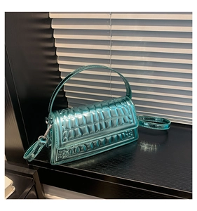 Close-up of metallic green crocodile textured handbag with sleek detachable shoulder strap