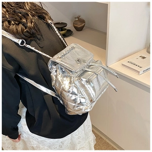 Detail of silver quilted backpack showing heart metal lock and chain shoulder strap