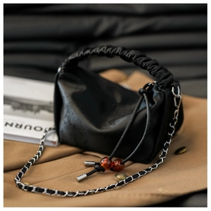 Détail de la poignée froncée et de la perle ambrée sur le sac plissé noir chic