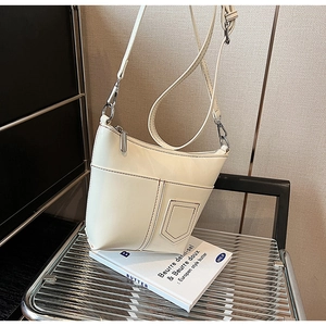 Detailansicht der cremefarbenen Umhängetasche mit Vordertasche und verstellbarem Gurt