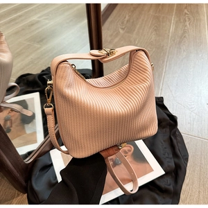 Détail d'un sac à main plissé rose clair avec fermoir doré et bandoulière en cuir fin