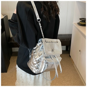 Detail of silver metallic backpack featuring quilted side stitching and heart metal buckle