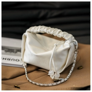 Gros plan d'un sac ivoire avec poignée plissée et bandoulière en chaîne argentée