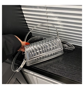 Detail of silver metallic handbag featuring checkered stitching and smooth handles
