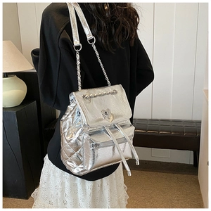 Detail of silver quilted backpack featuring heart-shaped lock and metal chain straps