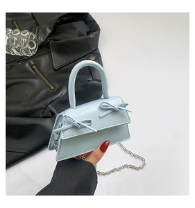 Close-up of light blue mini handbag with double bow accents and silver chain strap