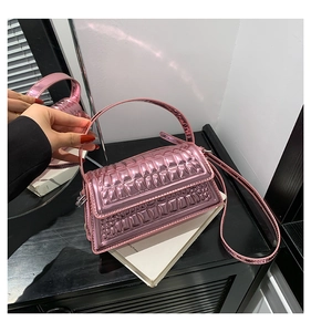 Detail of glossy metallic pink handbag featuring embossed wave texture and top handle