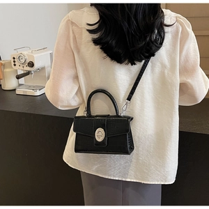 Rear view of a black crocodile pattern crossbody bag showing style and size on model