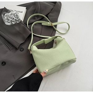Gros plan sur la texture plissée vert sauge d'un sac en cuir avec détails dorés