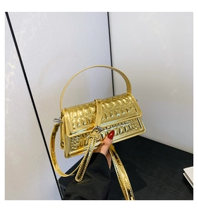 Detail of glossy gold metallic crossbody bag with textured crocodile pattern and top handle