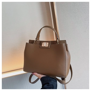 Detail view of brown pebbled leather handbag featuring a golden metal turn-lock closure