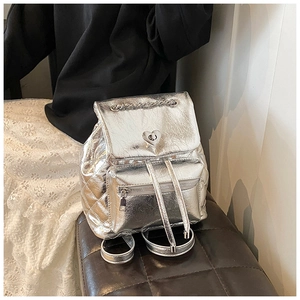 Close-up of quilted silver backpack featuring a heart-shaped twist lock and metallic finish