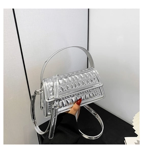 Detail of silver metallic handbag with square embossed texture and adjustable strap