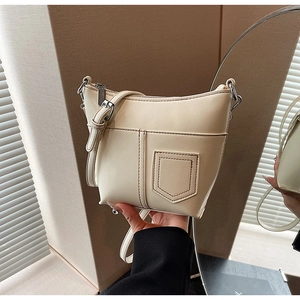 Detail der cremefarbenen Ledertasche mit silbernem Reißverschluss und verstellbarem Riemen
