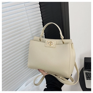 Detail of cream tote bag featuring pebbled leather texture and gold twist lock closure