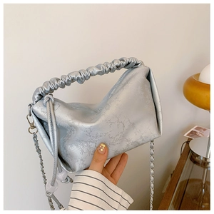 Détail du sac à main bleu argenté avec texture florale et poignée plissée chic