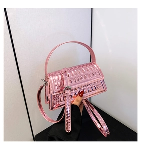 Detail of metallic pink crossbody bag featuring 3D crocodile pattern and glossy finish
