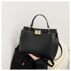 Detail of black pebbled leather tote bag featuring gold twist lock and sturdy top handle