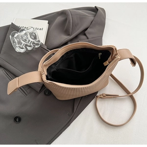 Détail du sac bandoulière beige plissé avec texture rayée et fermeture éclair dorée