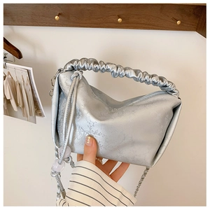 Détail du sac à main plissé argenté avec fini métallique et chaîne à perles décorative