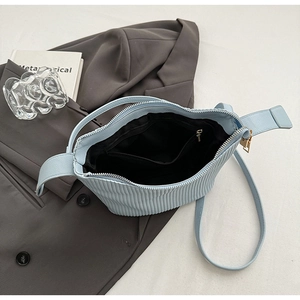 Détail du sac à main bleu clair plissé montrant la poche zippée intérieure et la texture