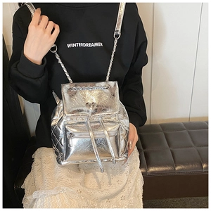Close-up of metallic silver quilted backpack with heart-shaped twist lock and chain strap