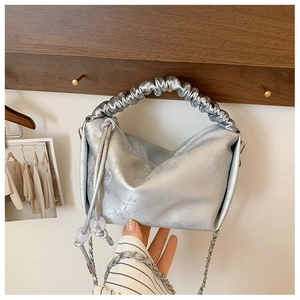 Détail du sac à main plissé argenté avec motif de bambou et cordon à perles
