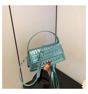 Detail view of bright blue glossy handbag with crocodile pattern and silver metal hardware