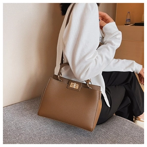 Close-up of brown litchi grain tote bag featuring a prominent gold square twist lock