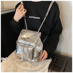 Detail of silver metallic backpack featuring heart-shaped twist lock and chain strap