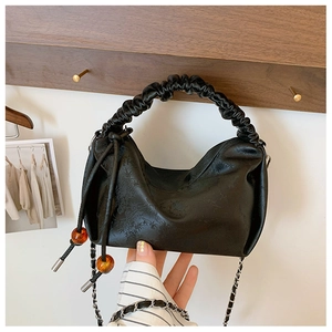 Détail du sac à main à poignée plissée avec perles ambrées et bandoulière chaîne