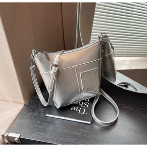 Detailaufnahme der silbernen Metallic-Umhängetasche mit Nähten und Metallreißverschlüssen