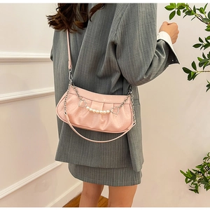 Détail du sac à main plissé rose avec chaîne de perles et breloque en forme de cœur