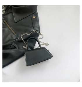 Detail of a black textured leather mini handbag with silver chain strap and top handle