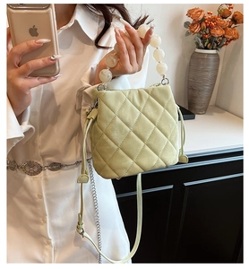 Détail du sac seau matelassé vert clair avec poignée en perles et détails de cordon