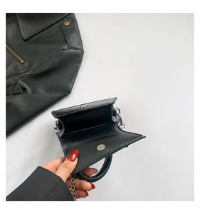 Detail of mini black leather bag showing silver magnetic closure and detachable chain strap