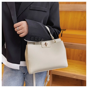 Detail view of cream-colored pebble leather tote bag featuring gold twist-lock closure