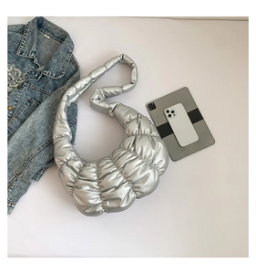 Chic silver pleated crescent bag with metallic finish shown on a flat lay grey background
