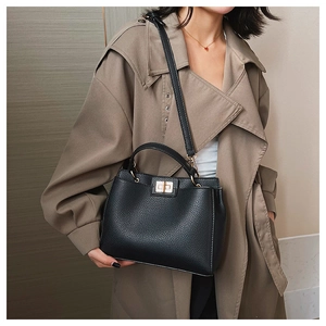 Detail of black lychee grain leather tote with gold turn-lock and adjustable shoulder strap