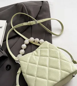 Détail du sac seau matelassé vert clair avec poignée en perles et rivets en métal