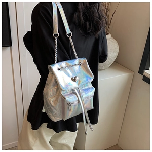 Detail of silver iridescent backpack featuring heart lock and chain strap on model