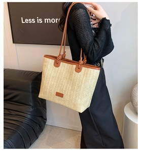 Detail of woven straw tote bag with brown leather handles and decorative knot accents