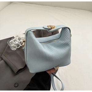 Détail du sac à main plissé bleu clair avec boucle cœur dorée et texture verticale